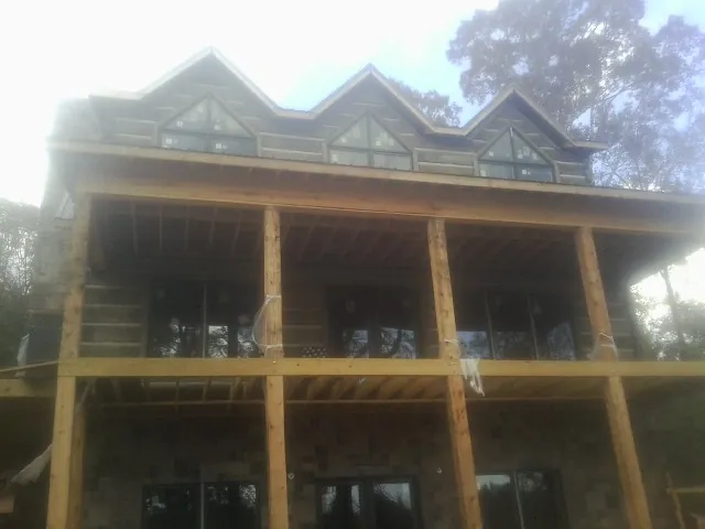 Dormers and porch framing on a large log home under construction — Roof Coating work by our crew in Capitol Heights