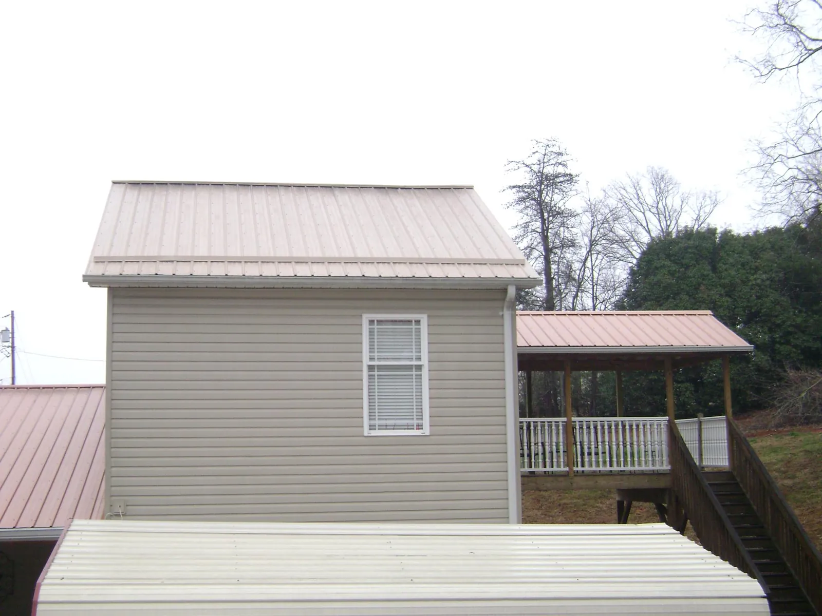 Tan metal roofs on a two story addition and attached porch, from a Roof Replacement job in Capitol Heights