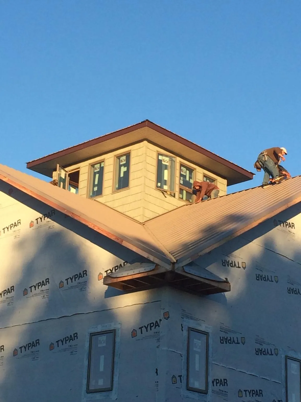Roofers working around a rooftop cupola on a new metal roof at sunset — Roof Waterproofing in Capitol Heights by Roofing Brothers